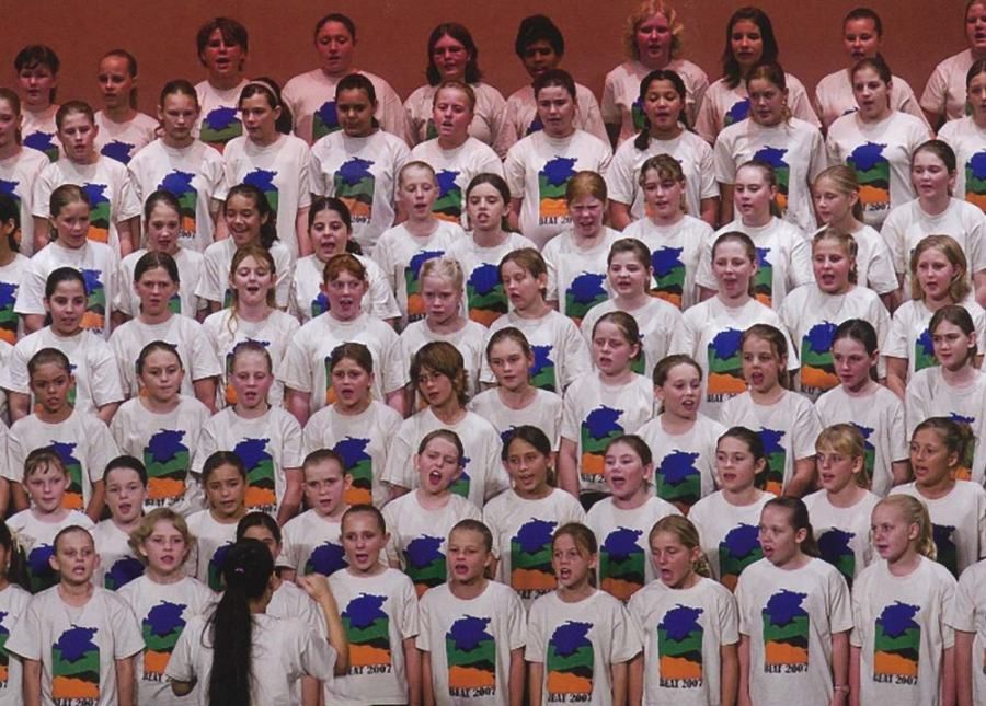 A large group of young girls are singing in a choir