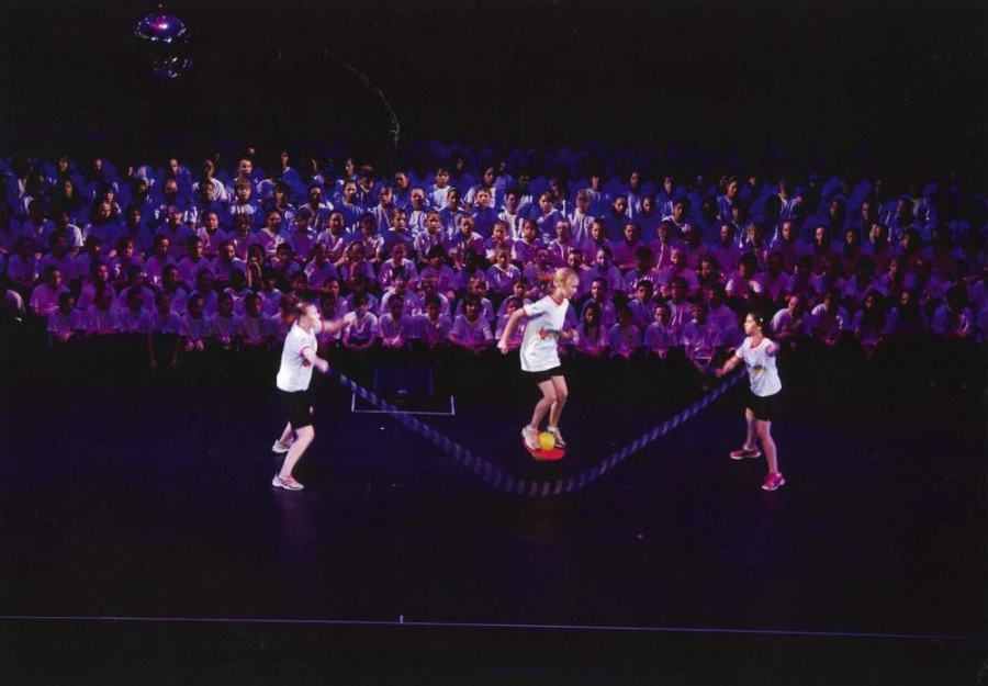 A group of people are playing soccer on a stage in front of a crowd