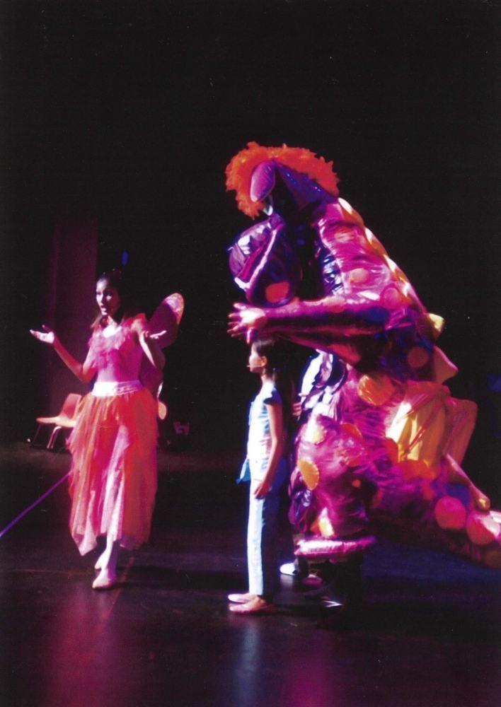 A clown is hugging a little girl on a stage