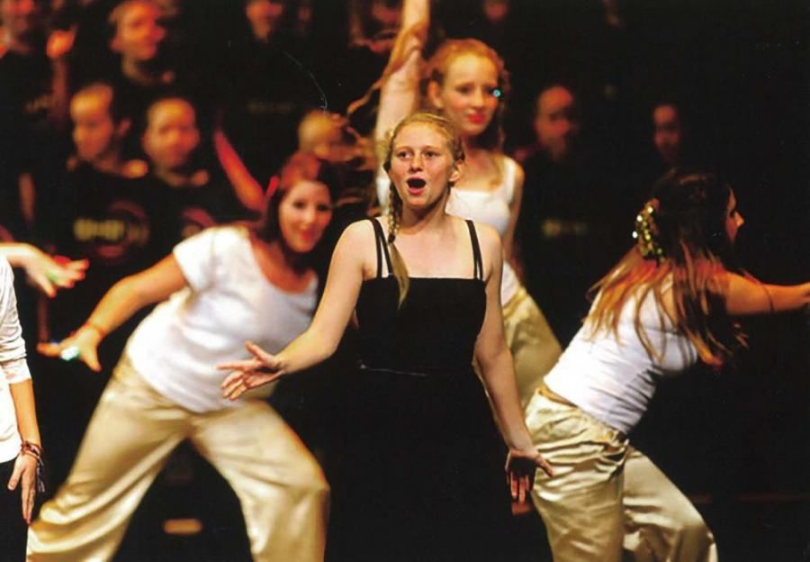 A group of young women are dancing on a stage in front of a crowd