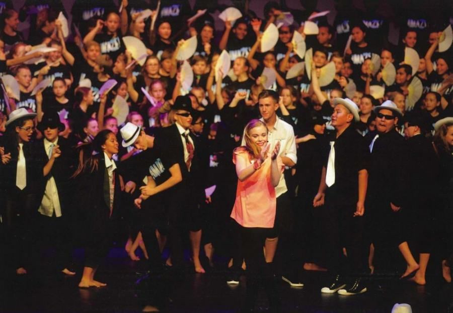 A group of people are standing on a stage and one of them is wearing a pink shirt