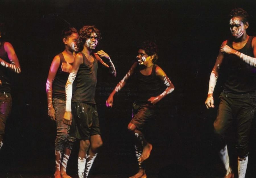 A group of people with their faces painted are dancing on a stage
