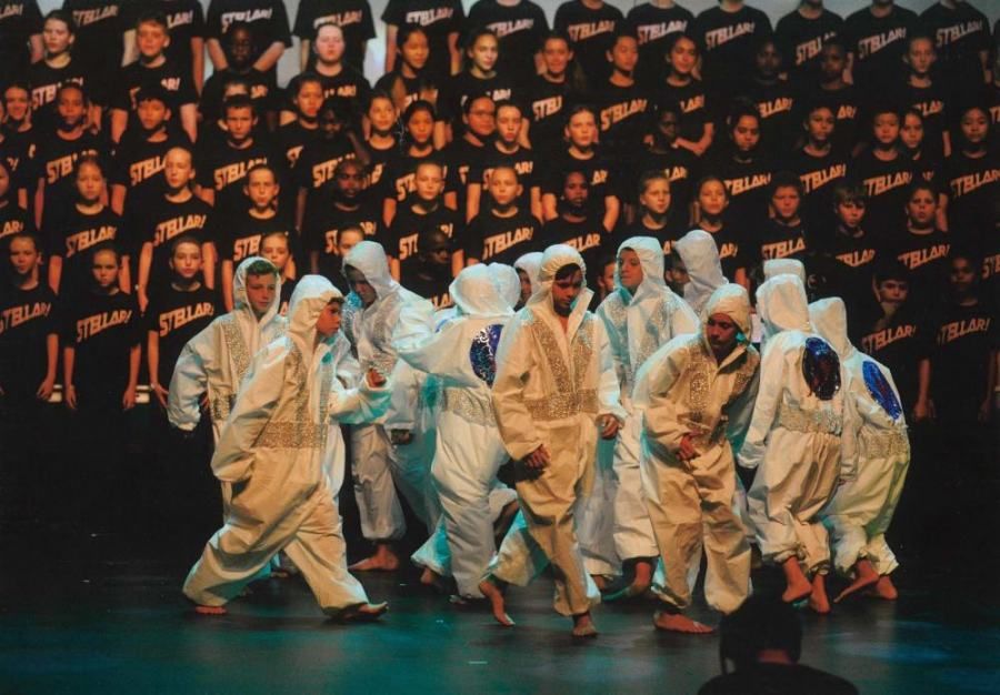 A group of people are dancing on a stage in front of a large crowd.