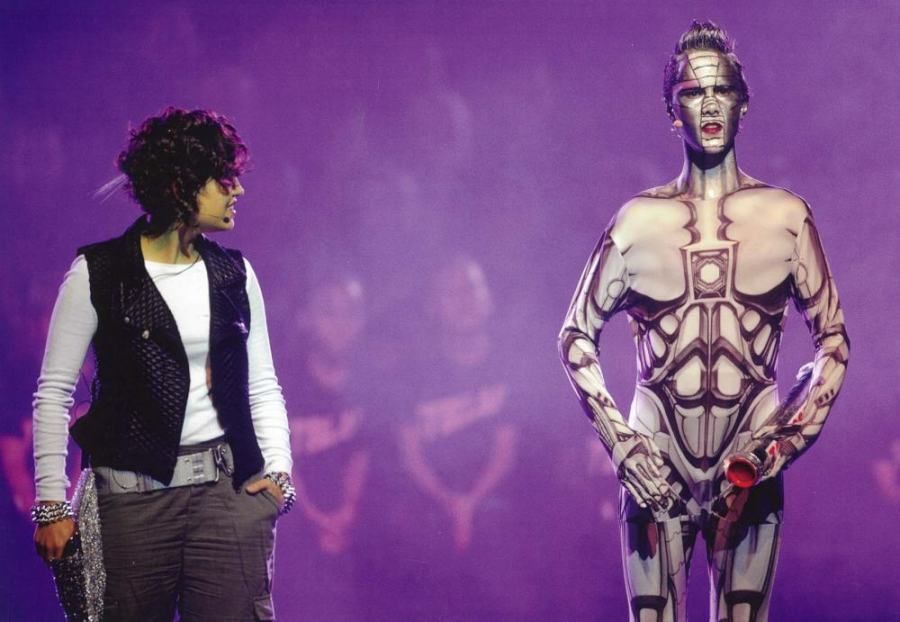 A woman is standing next to a man with his body painted