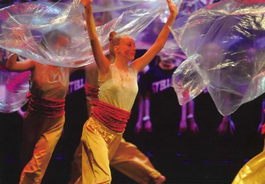 A woman in a white tank top is dancing with plastic bags