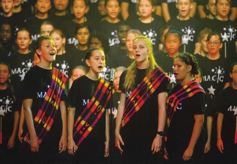 A group of young girls singing in front of a wall that says magic