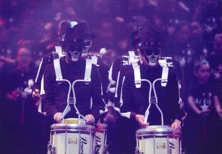 A marching band is playing drums in front of a crowd
