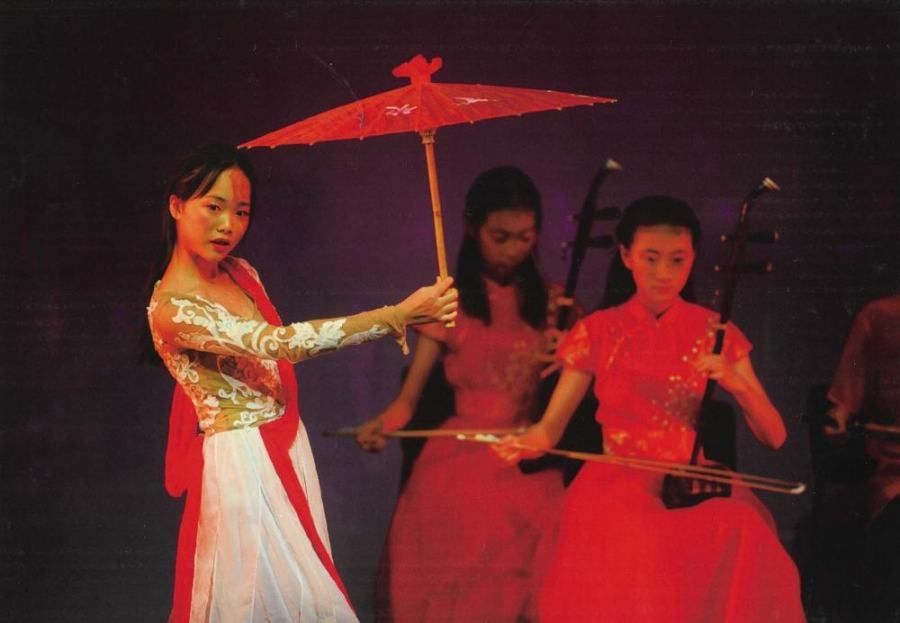 A woman in a red dress is holding a red umbrella