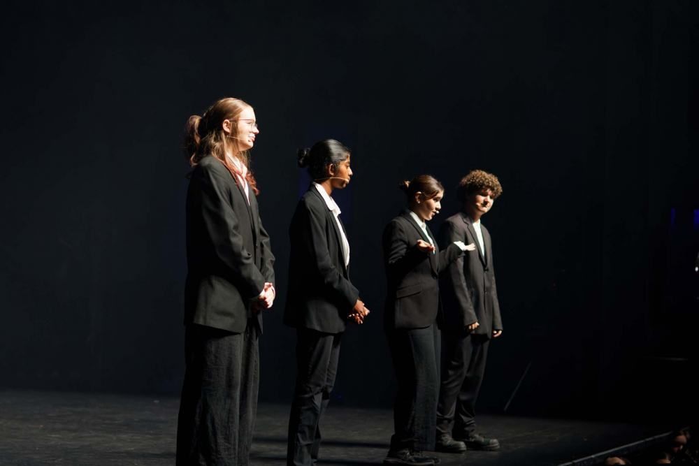 A group of people in suits are standing on a stage.