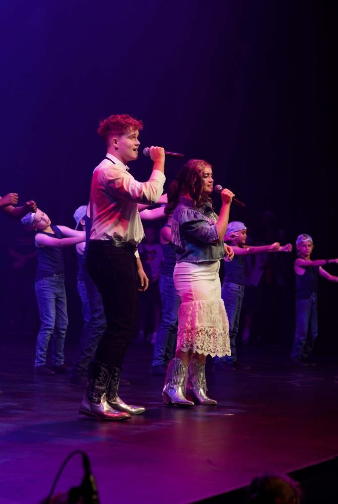 A man and a woman are singing into microphones on a stage.