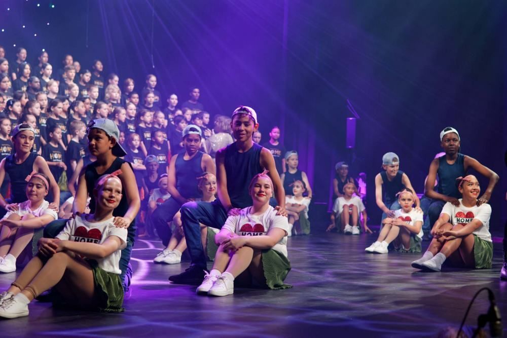 A group of people are sitting on the floor on a stage.