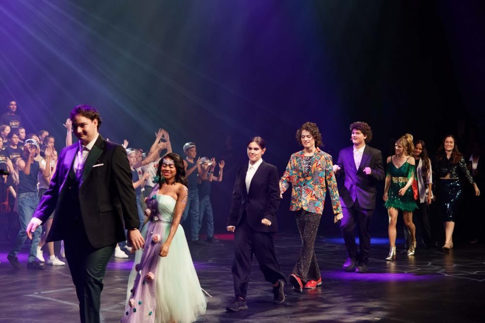 A group of people are walking on a stage in front of a crowd.