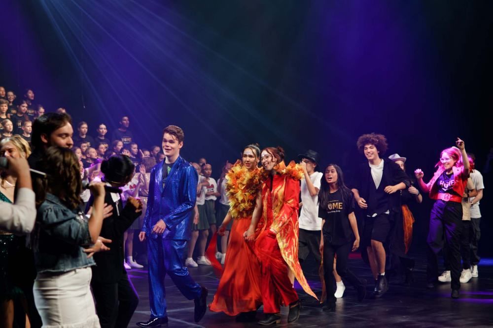 A group of people are dancing on a stage in front of a crowd.