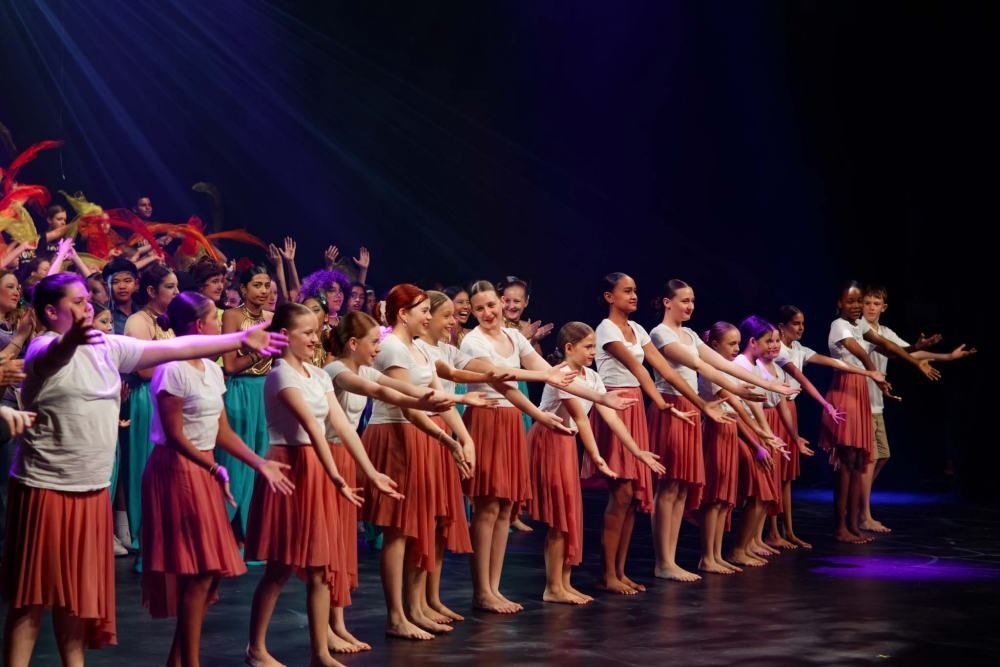 A group of young girls are standing in a row on a stage.