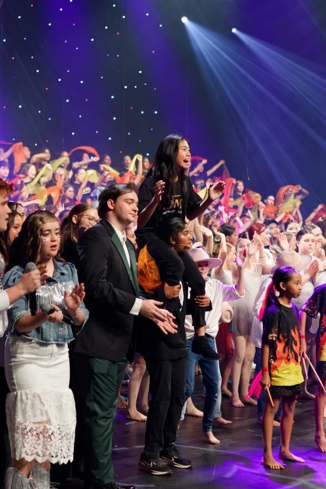 A group of people are standing on a stage with purple lights.