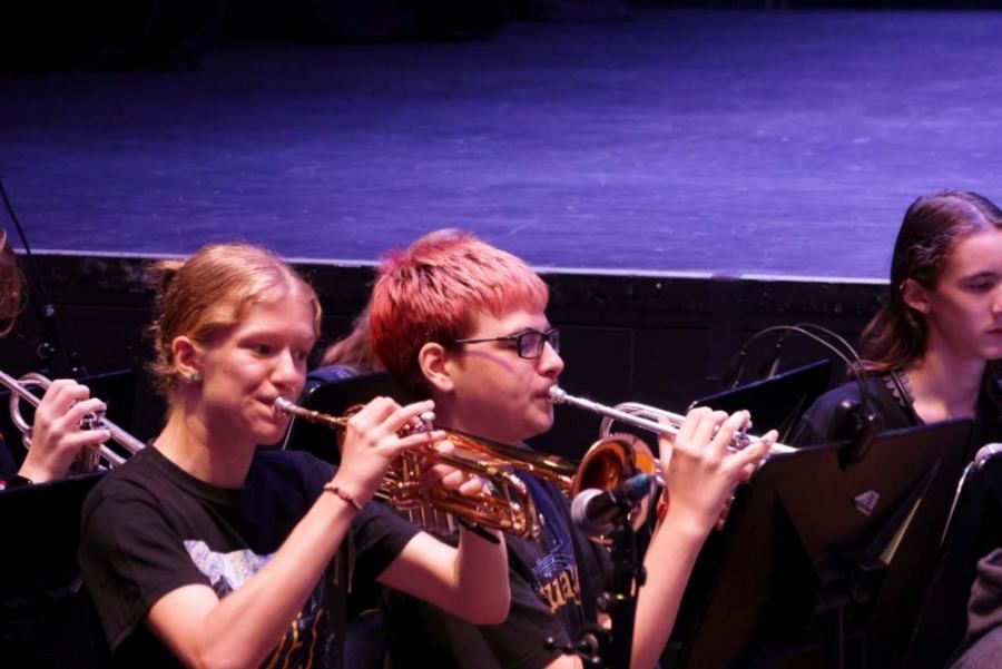 A group of young people are playing instruments on a stage.