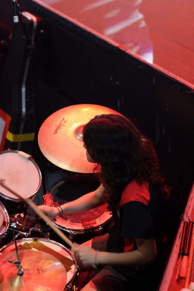 A woman is playing drums with a cymbal that says zildjian on it