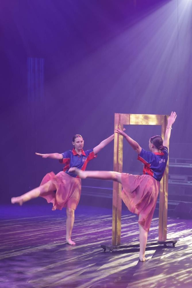 Two dancers are dancing in front of a mirror on a stage.