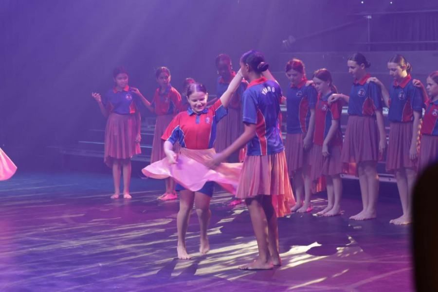 A group of young girls are dancing on a stage.