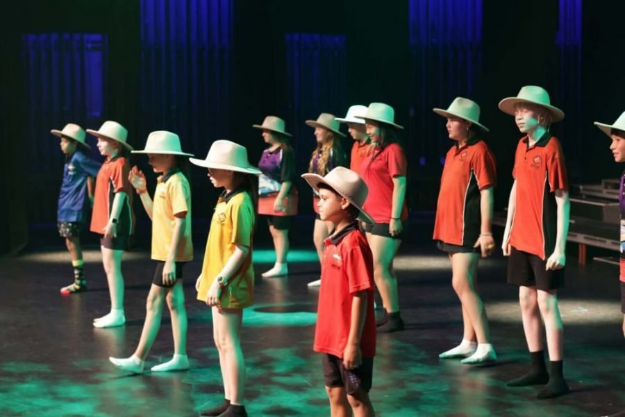 A group of children wearing hats are standing on a stage.