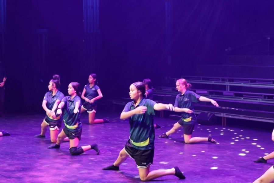 A group of young women are performing a dance on a stage.