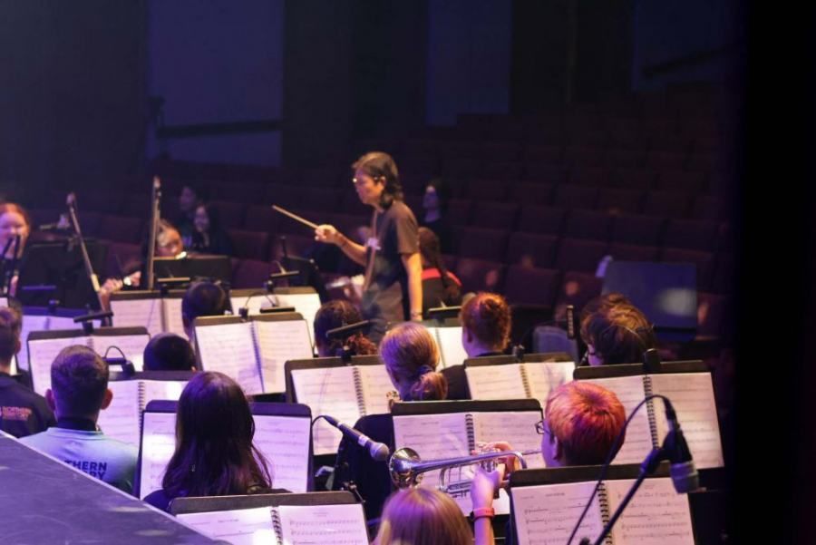 A woman is leading an orchestra on a stage.
