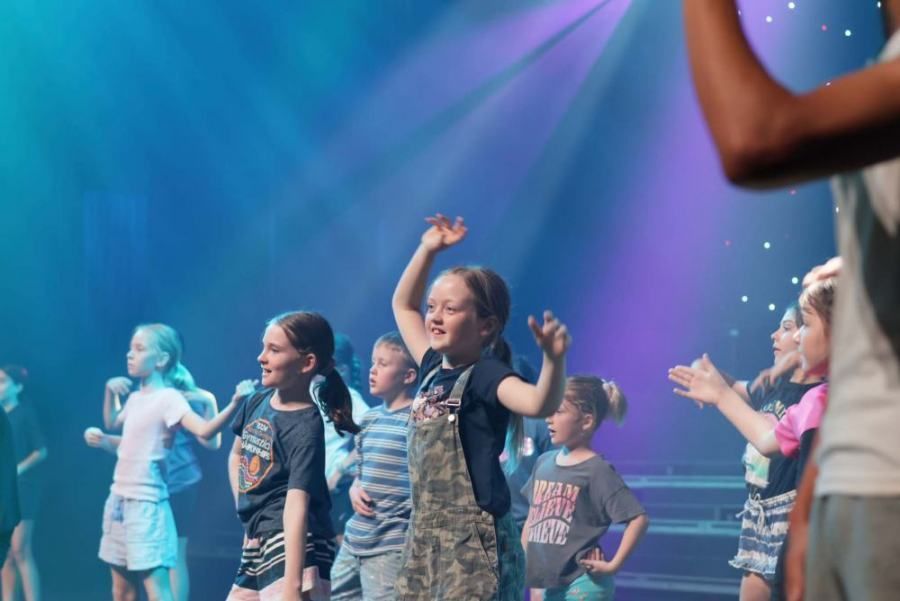 A group of young children are dancing on a stage.