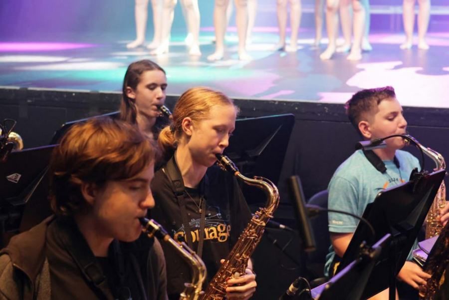 A group of young people are playing saxophones in an orchestra.