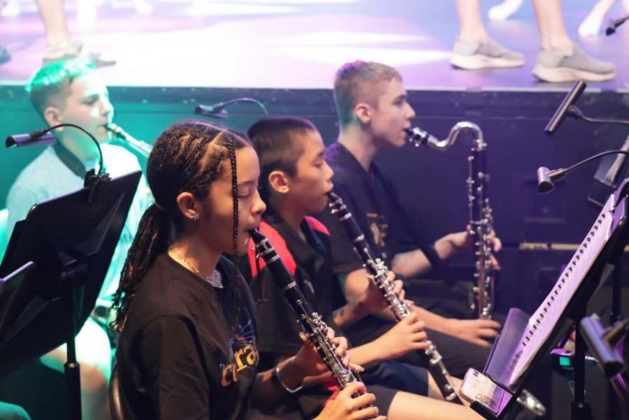 A group of young people are playing clarinets and saxophones on a stage.