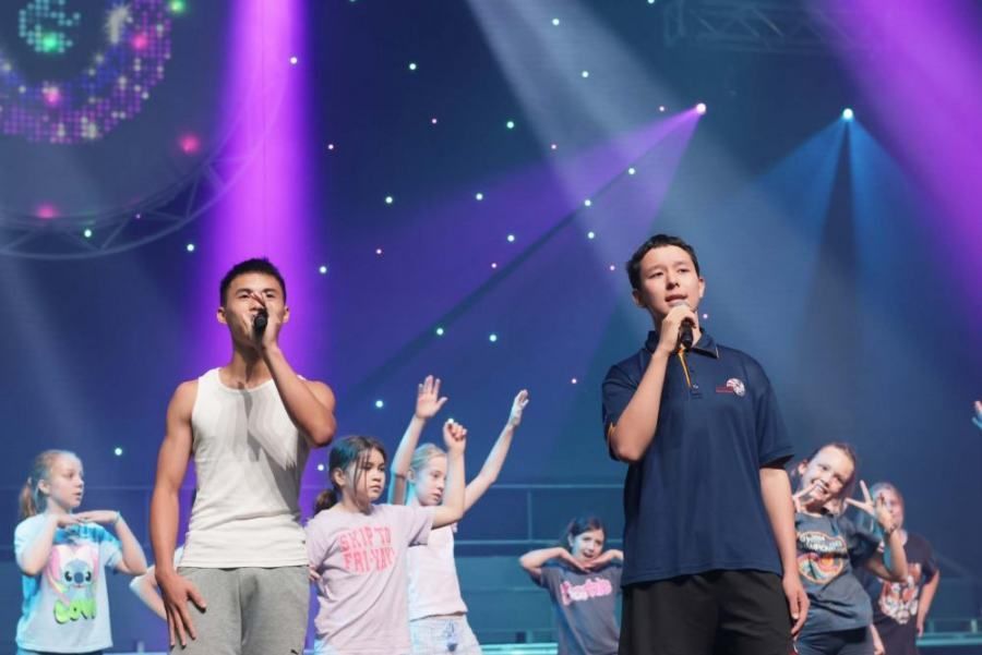 A group of people are singing into microphones on a stage.