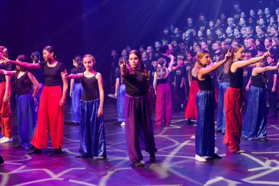 A group of young girls are dancing on a stage in front of a crowd.