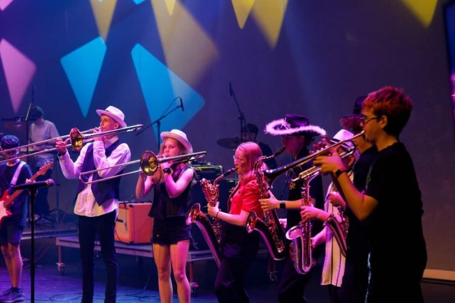 A group of young people are playing instruments on a stage.