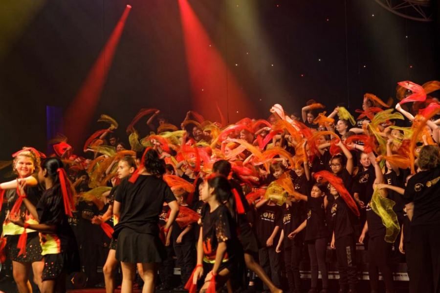 A large group of people are dancing on a stage.