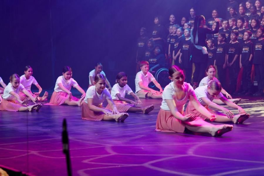 A group of young girls are doing stretching exercises on a stage.