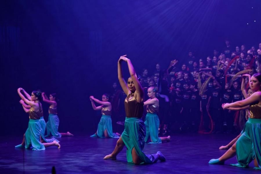 A group of women are dancing on a stage in front of a crowd.