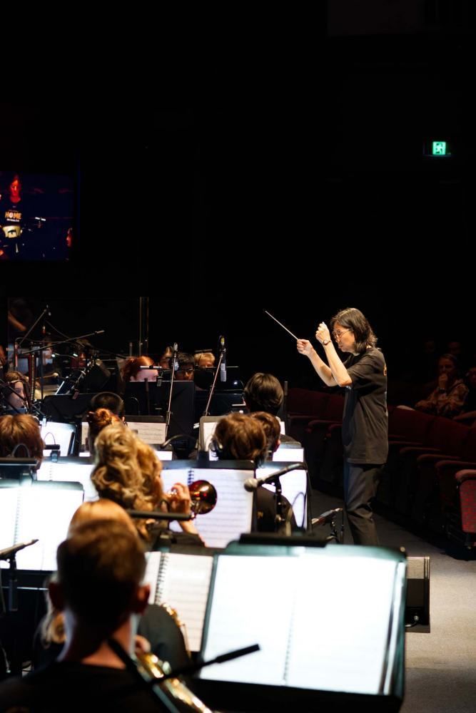 A man is leading an orchestra on a stage.