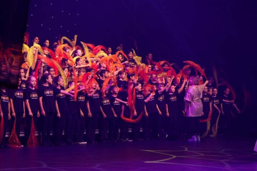 A large group of people are standing on a stage holding ribbons.