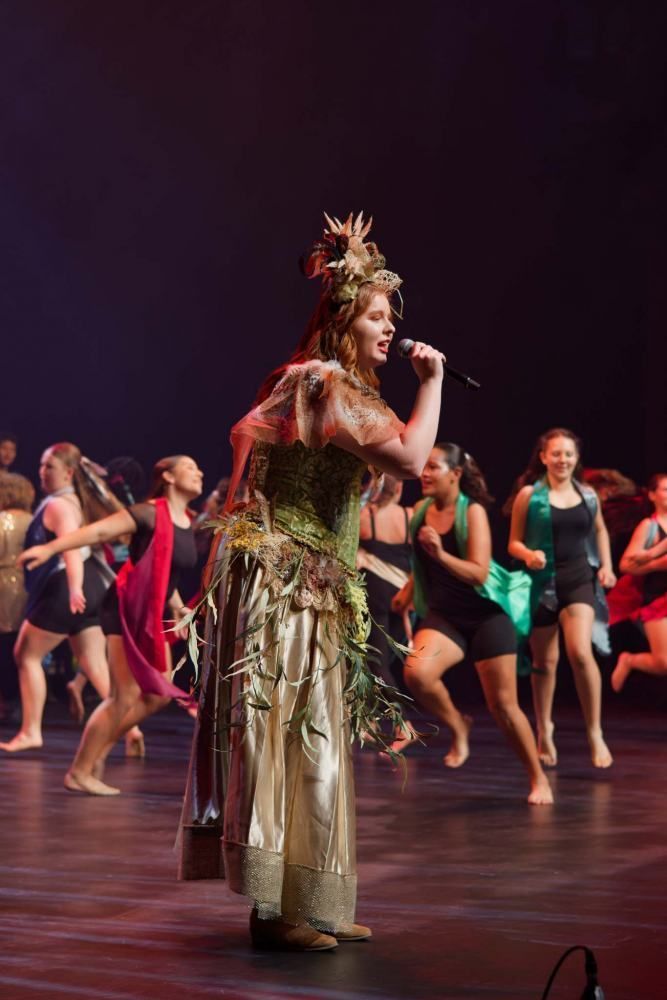A woman in a costume is singing into a microphone on a stage.