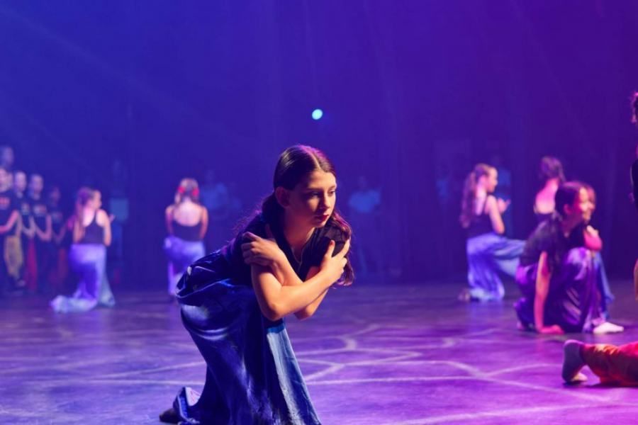 A group of people are dancing on a stage in a dark room.