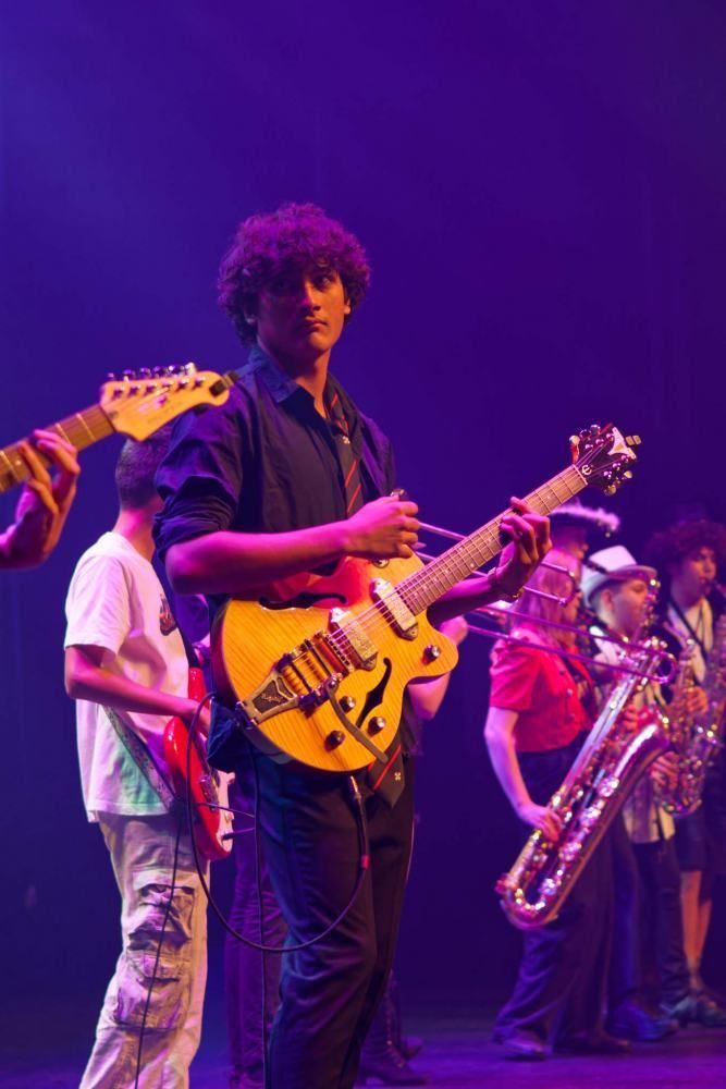 A man is playing a guitar in a band on a stage.
