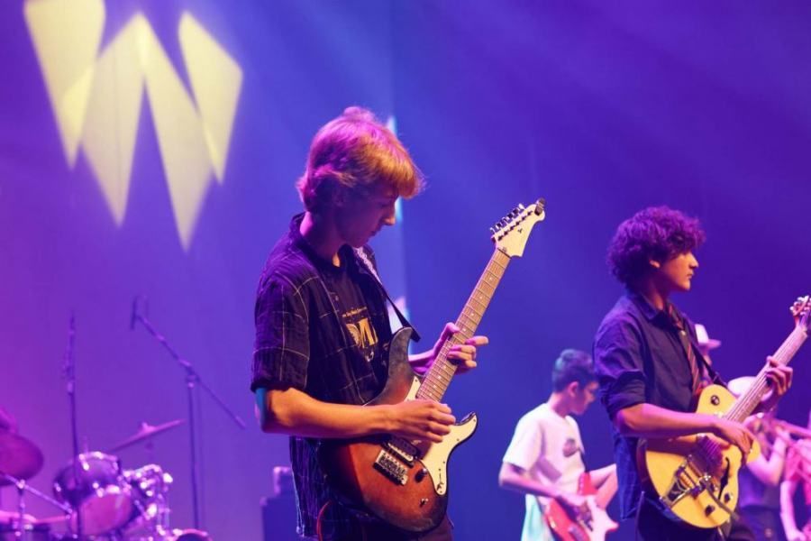 A group of young men are playing guitars on a stage.