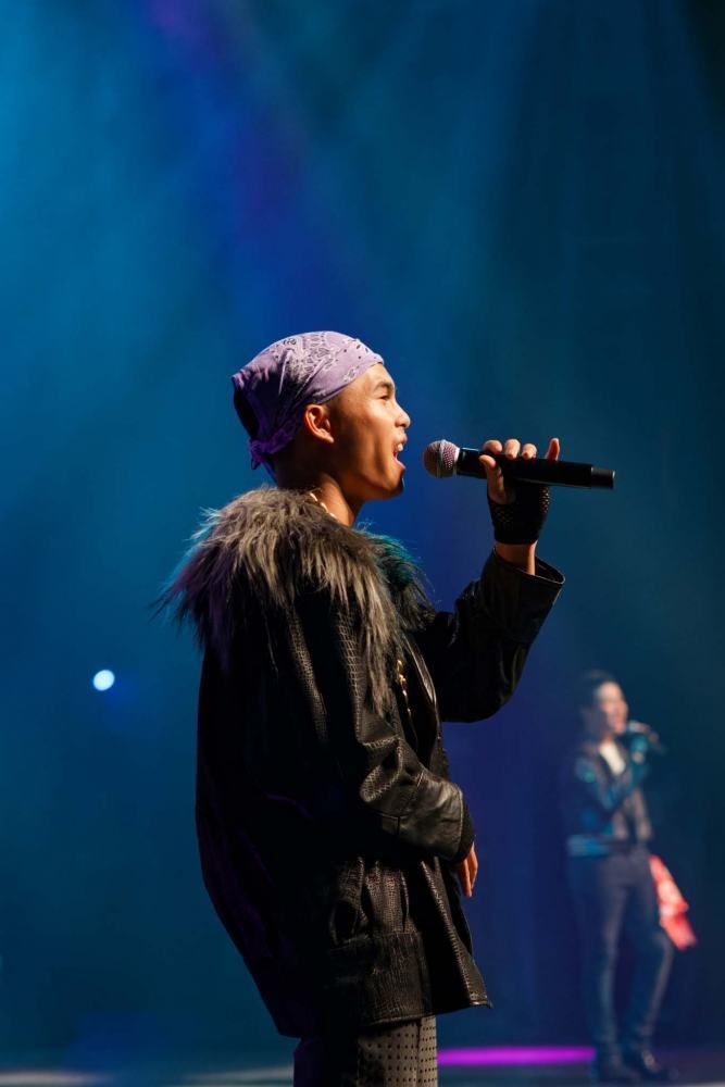 A man is singing into a microphone on a stage.