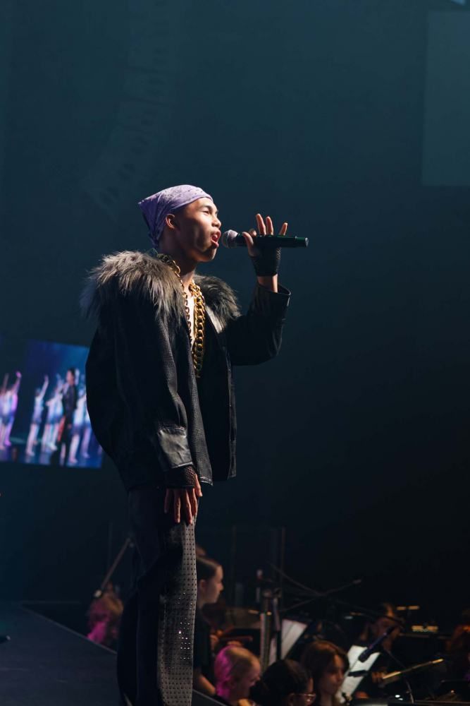 A man in a fur coat is singing into a microphone on a stage.