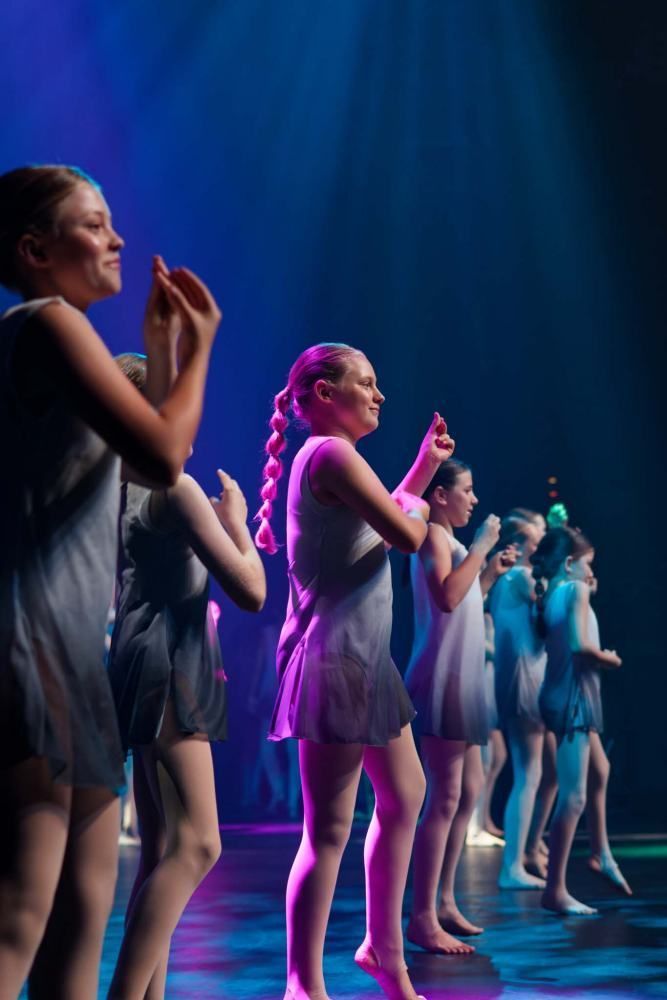 A group of young girls are dancing on a stage.