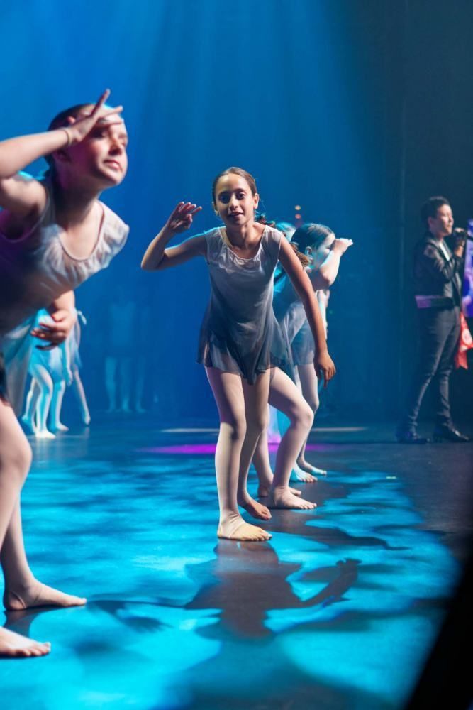 A group of young girls are dancing on a stage.