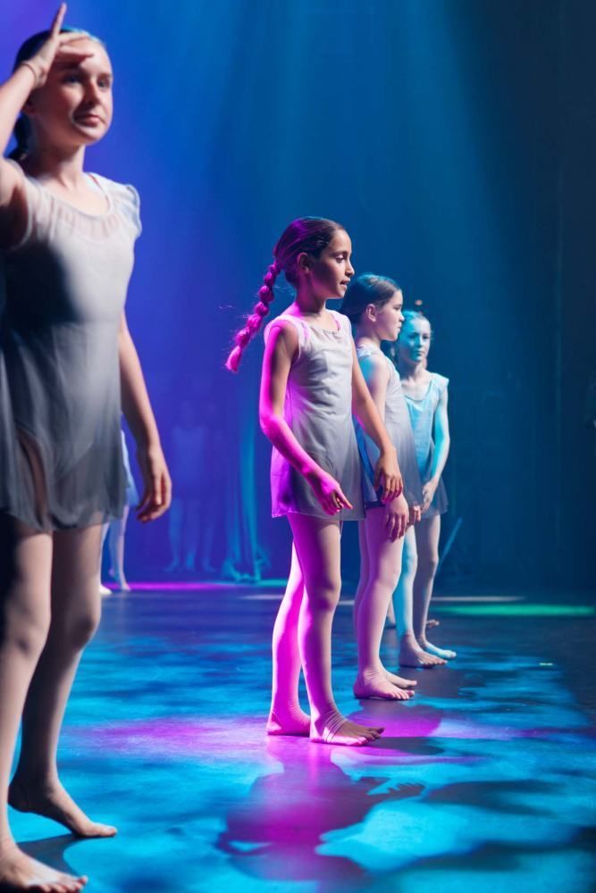 A group of young girls are standing on a stage in a row.