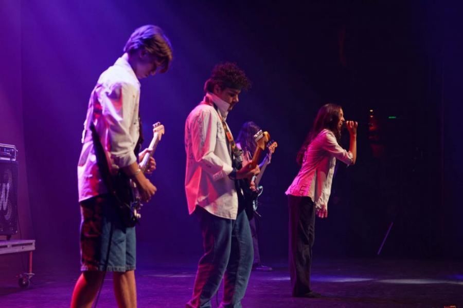 A group of people are playing guitars and singing on a stage.