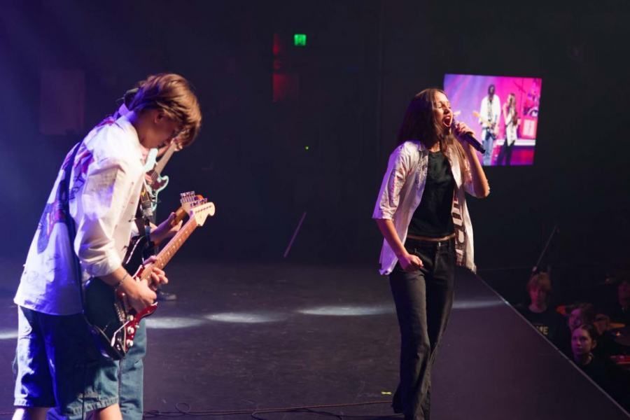 A man playing a guitar and a woman singing on a stage