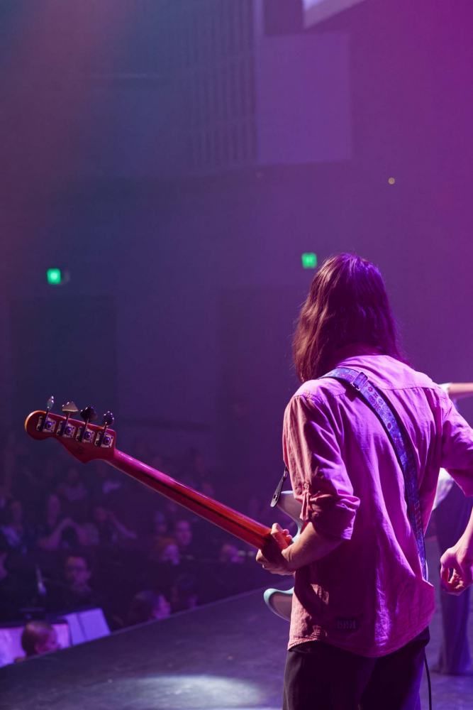 A man is playing a guitar on a stage in front of a crowd.