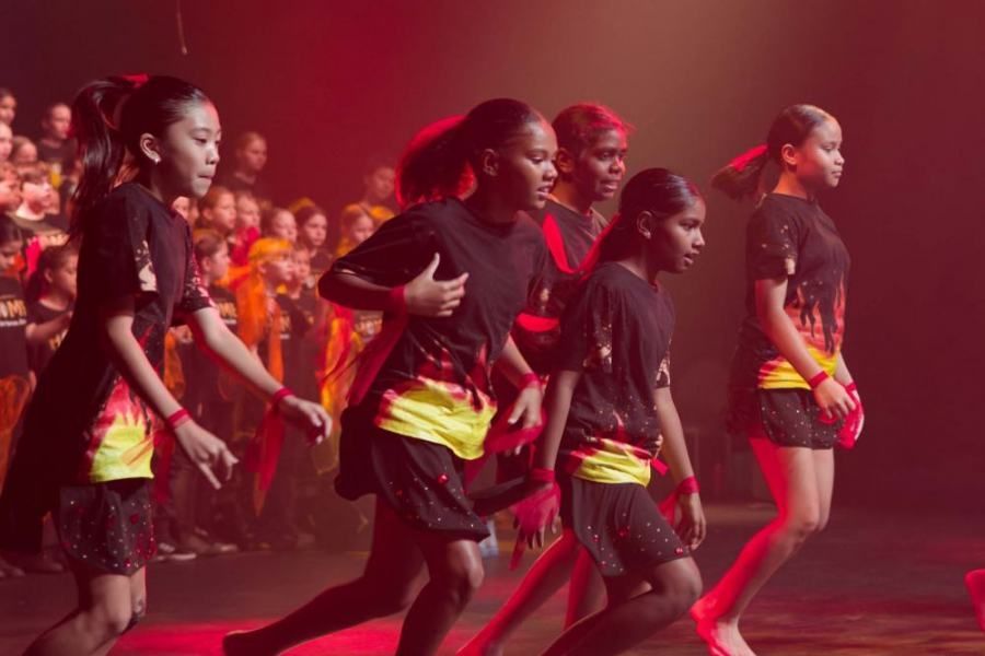 A group of young girls are dancing on a stage in front of a crowd.